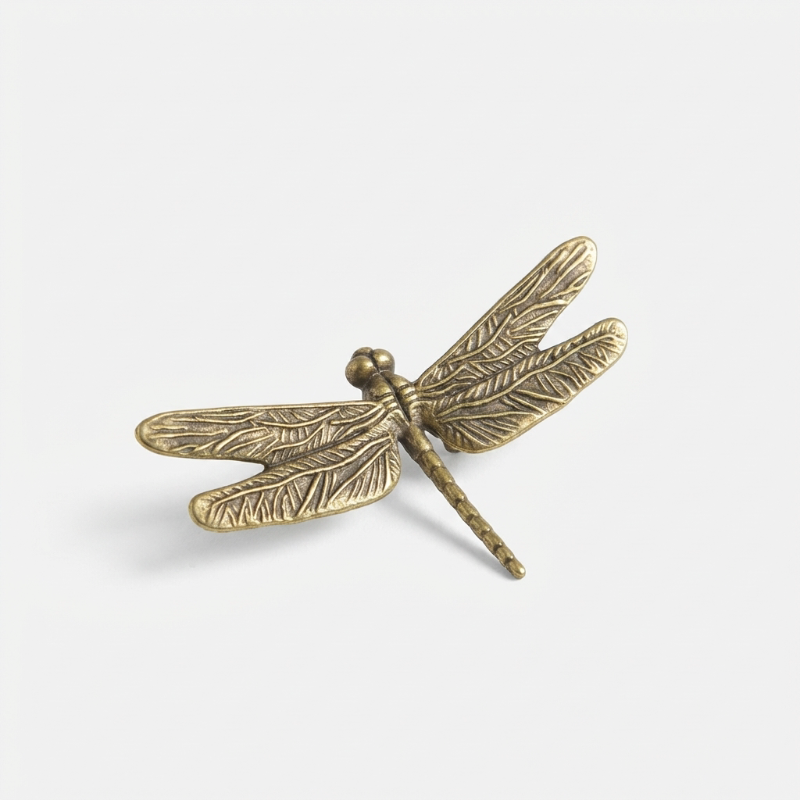 Bronze dragonfly-shaped object on a white background
