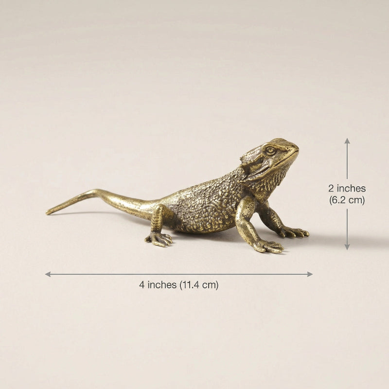 Bronze lizard figurine with measurements on a beige background