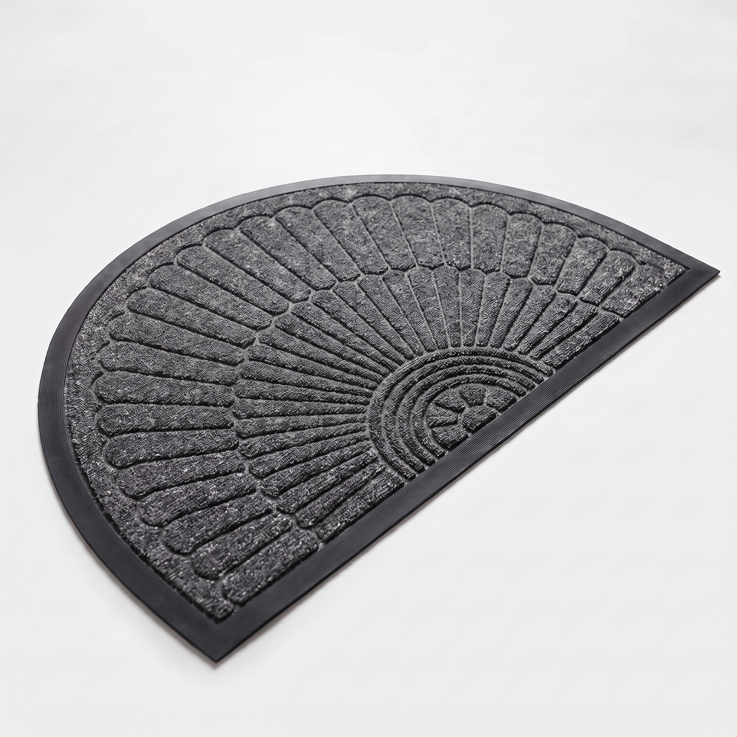 Dark grey crescent half-moon door mat with embossed sunburst design and black rubber border on a clean off-white background