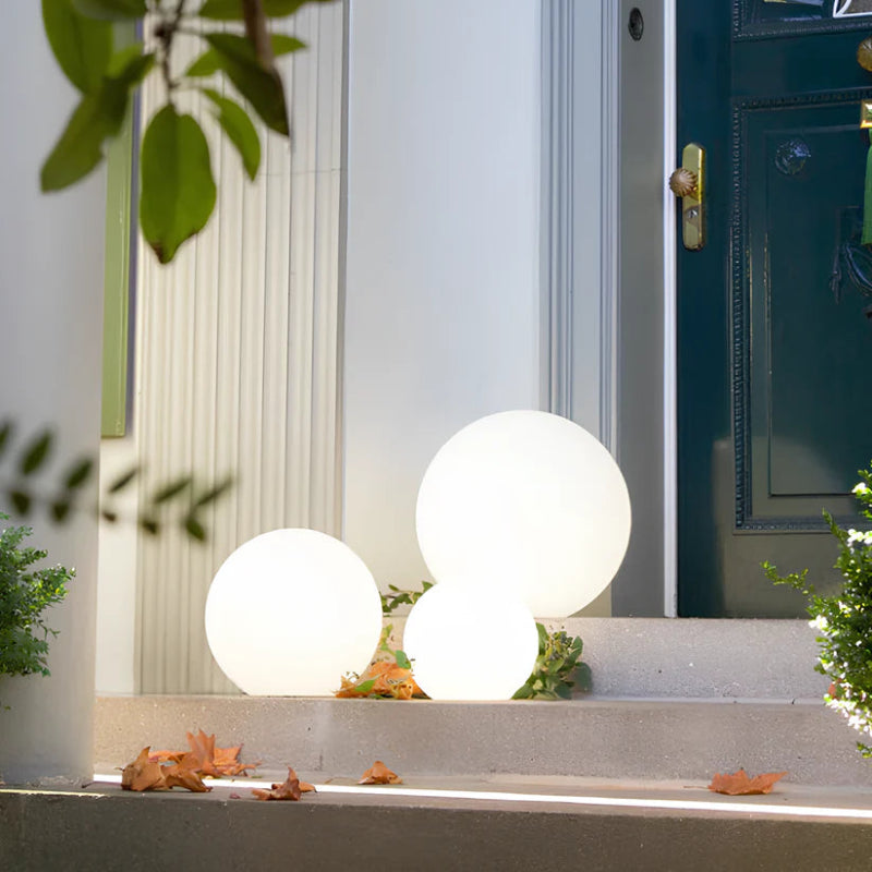 Three glowing white spherical lamps are on steps leading to a dark green door.