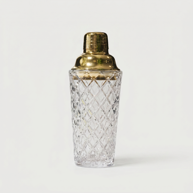 Glass cocktail shaker with gold lid on white background