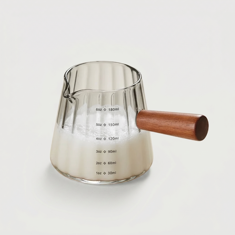 Green glass milk frothing pitcher on white background