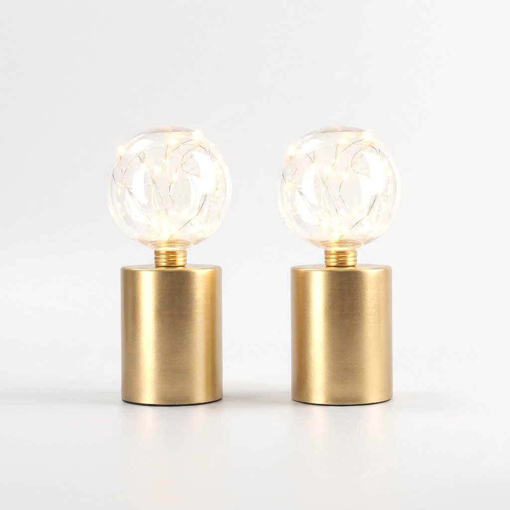Two lit clear glass globe LED lamps on brass bases, on a plain studio background