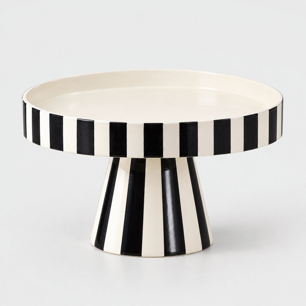 Black and white striped pedestal tray with a white interior shown at an angle on a plain light background