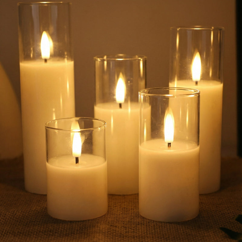 Set of five lit candles in glass holders on a textured surface.