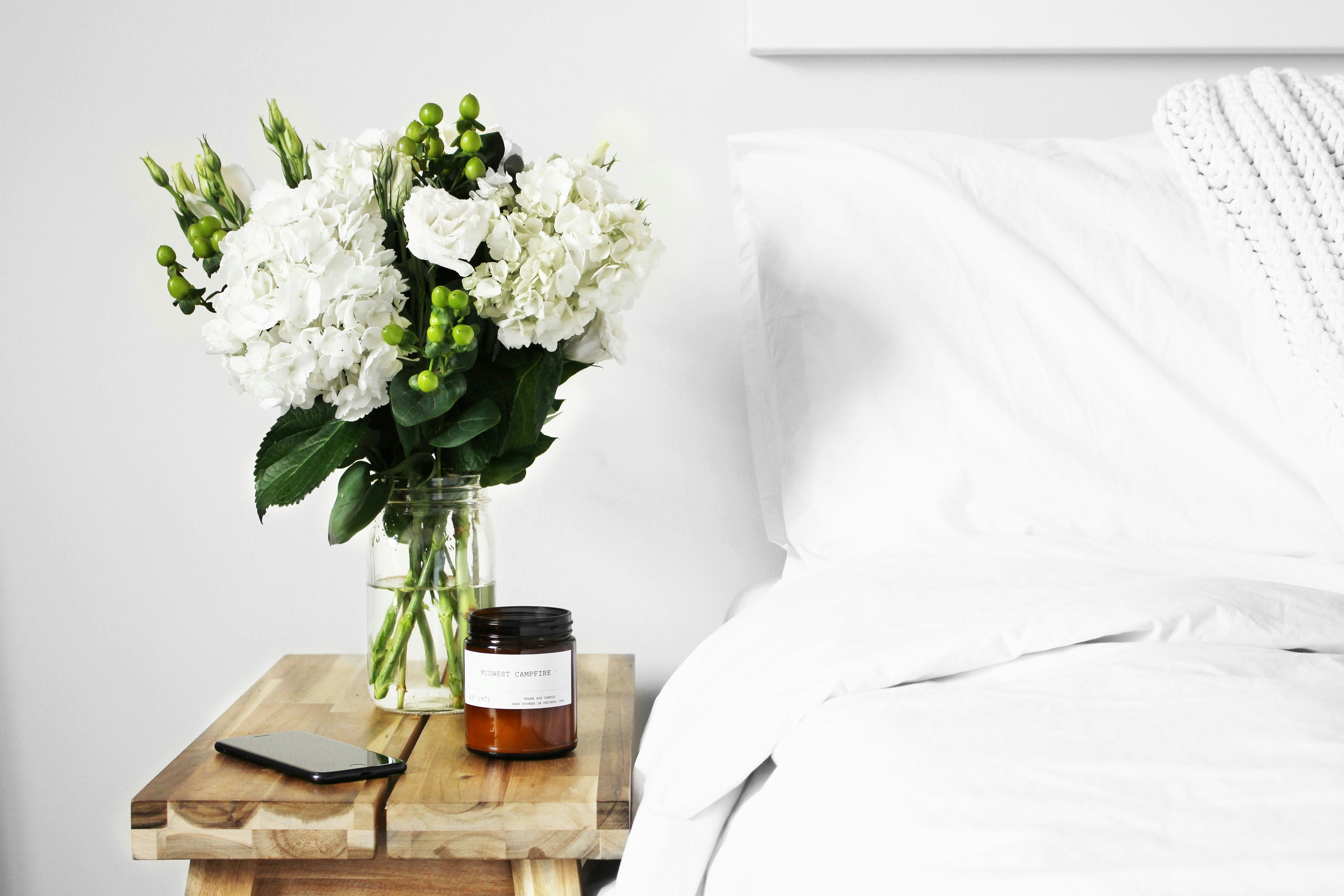 A cozy and stylish bedroom side table featuring delicate flowers, a softly glowing candle, and thoughtfully curated home accents from Kiyo Home.
