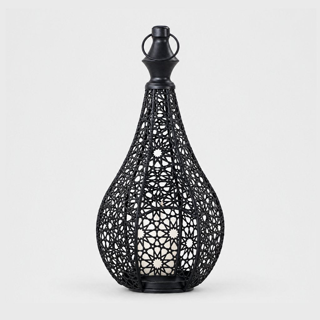 Black cutwork metal lantern with a pointed top and ring handle on a plain light background