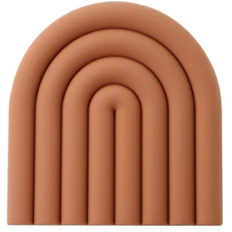 A rust-orange silicone trivet or coaster with a modern, segmented rainbow arch design is shown against a white background. The trivet has five raised, semi-circular segments.