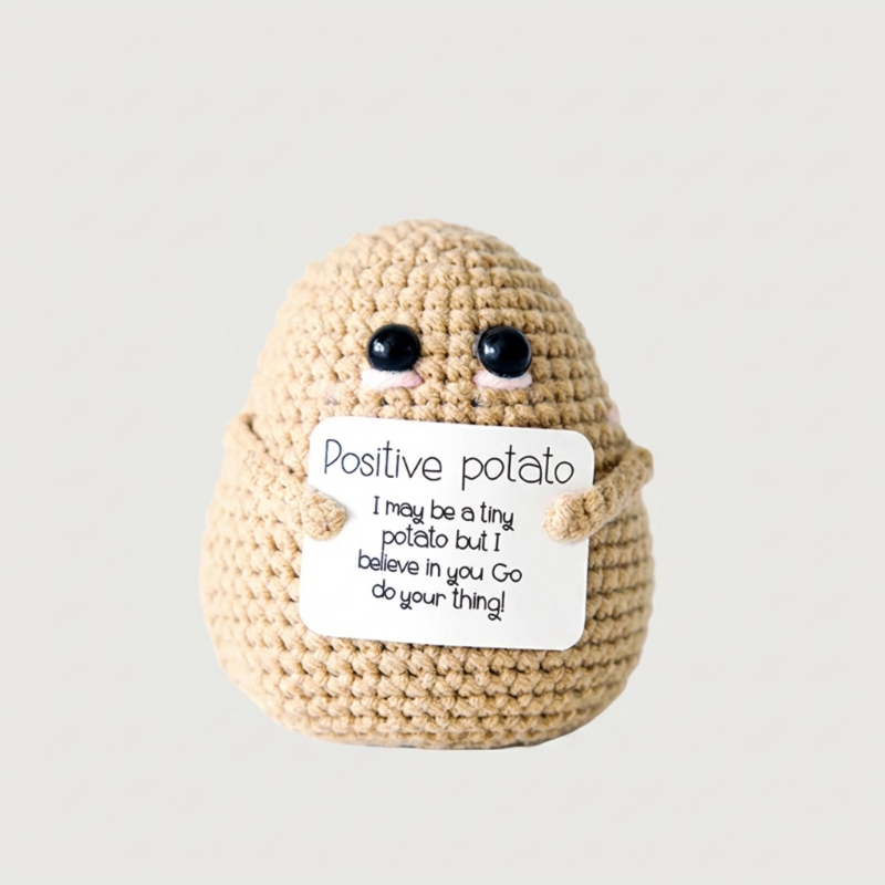 Crocheted potato plushie holding a sign with text on a plain background