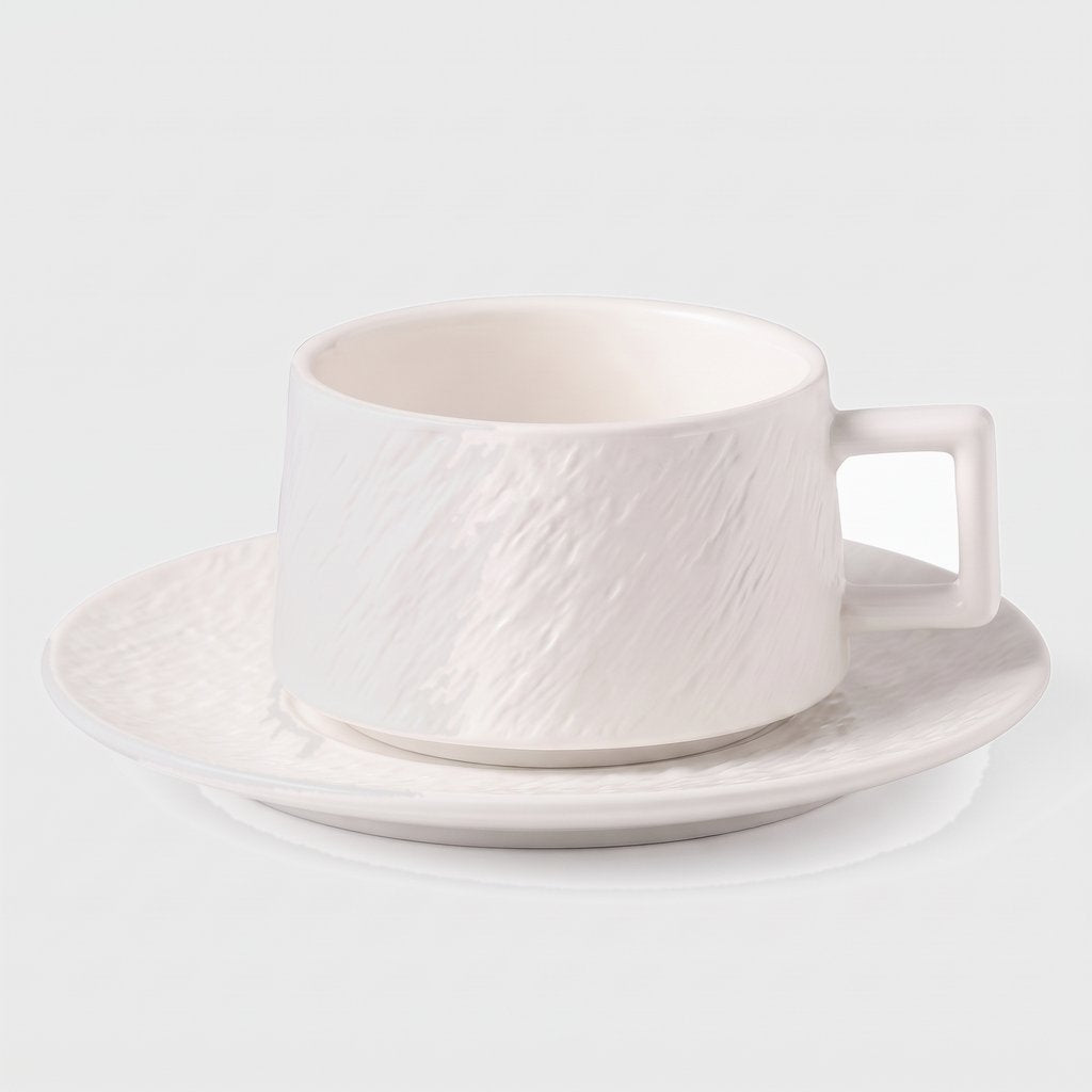 White textured ceramic cup on a matching saucer on a plain light background