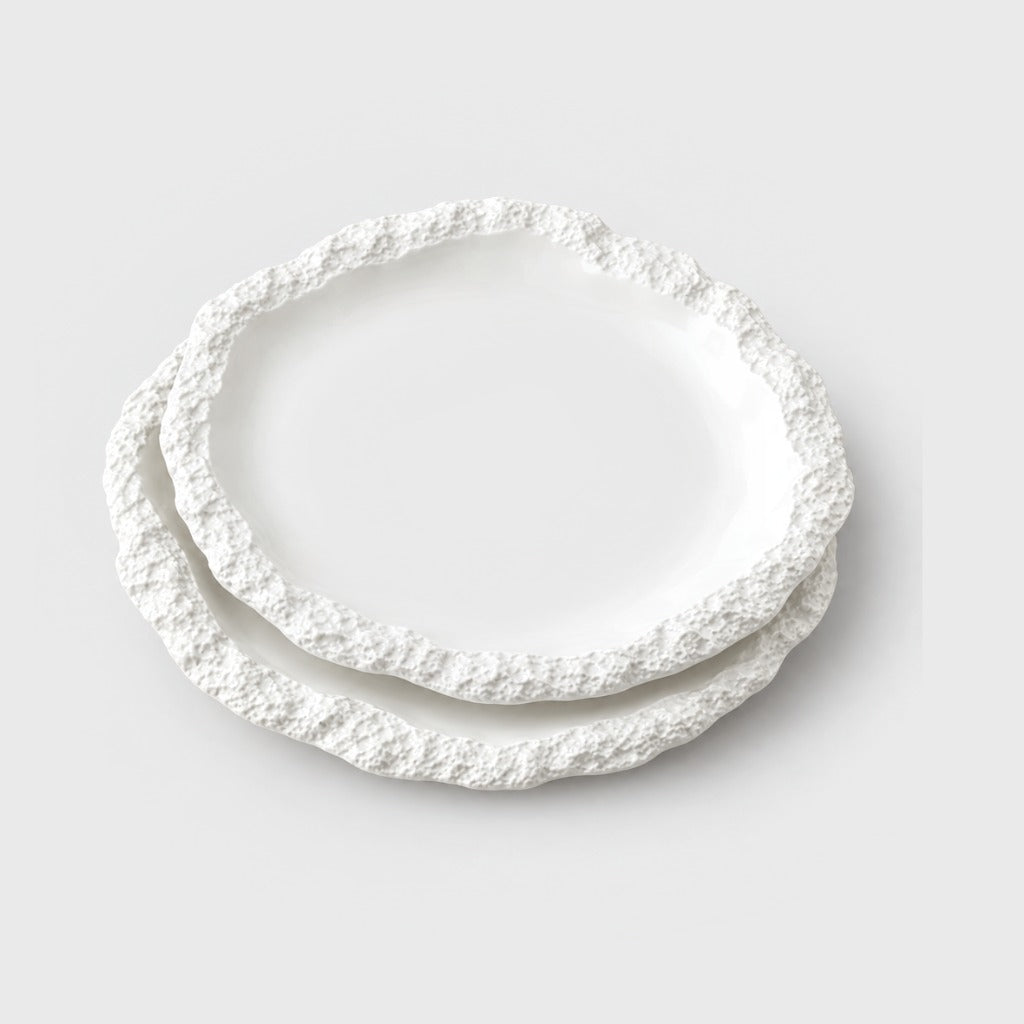 Two stacked white ceramic plates with a textured rim on a plain light background, the largest size in the range