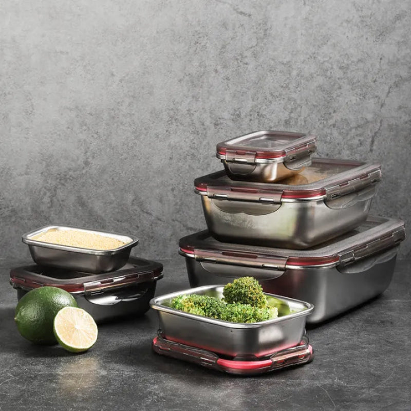An assortment of stainless steel food containers, some filled with food, arranged on a dark surface.