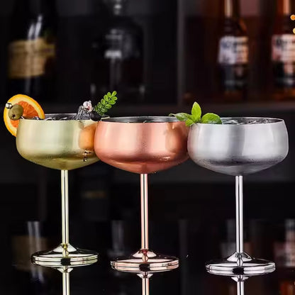 Three cocktail glasses with different colored drinks on a bar counter.