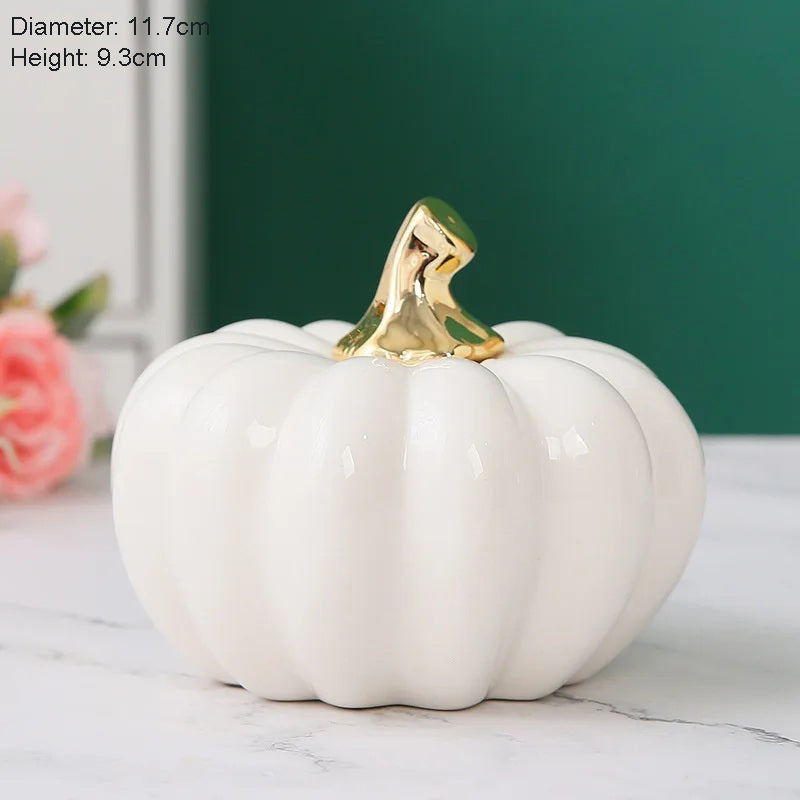 A single glossy white ceramic pumpkin with a golden stem sits on a marble surface, with text indicating its diameter and height.
