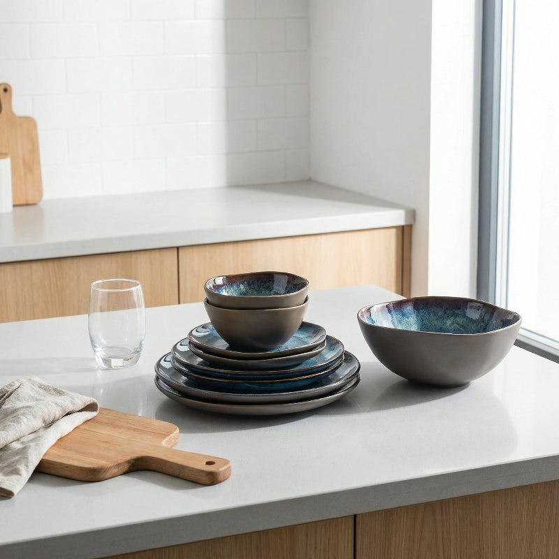 Set of ceramic bowls and plates on a kitchen counter with a window in the background.