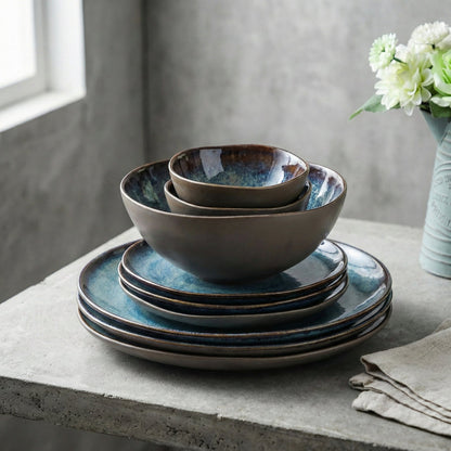 Set of ceramic bowls and plates with blue and brown glaze on a concrete surface.