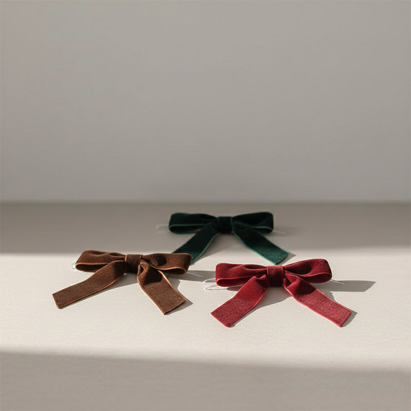 Three velvet ribbon bows in red, brown, and deep green.
