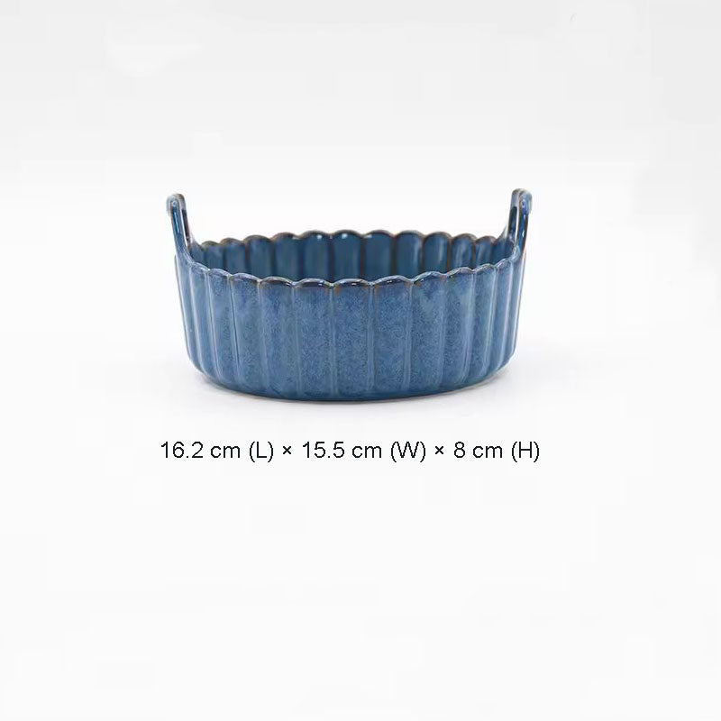 A blue ceramic baking dish with scalloped edges and two small handles.