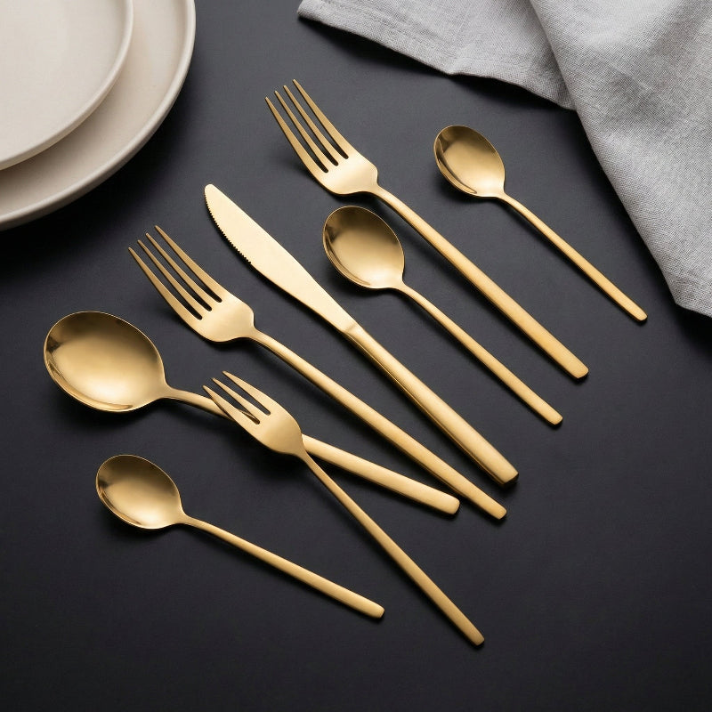Gold cutlery set on a dark surface with a light gray napkin.
