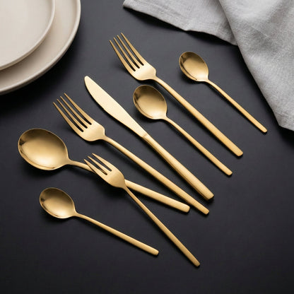 Gold cutlery set on a dark surface with a light gray napkin.