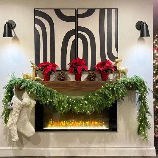 Decorative Christmas mantel with garlands, poinsettias, and stockings against a wall with abstract black and white design.