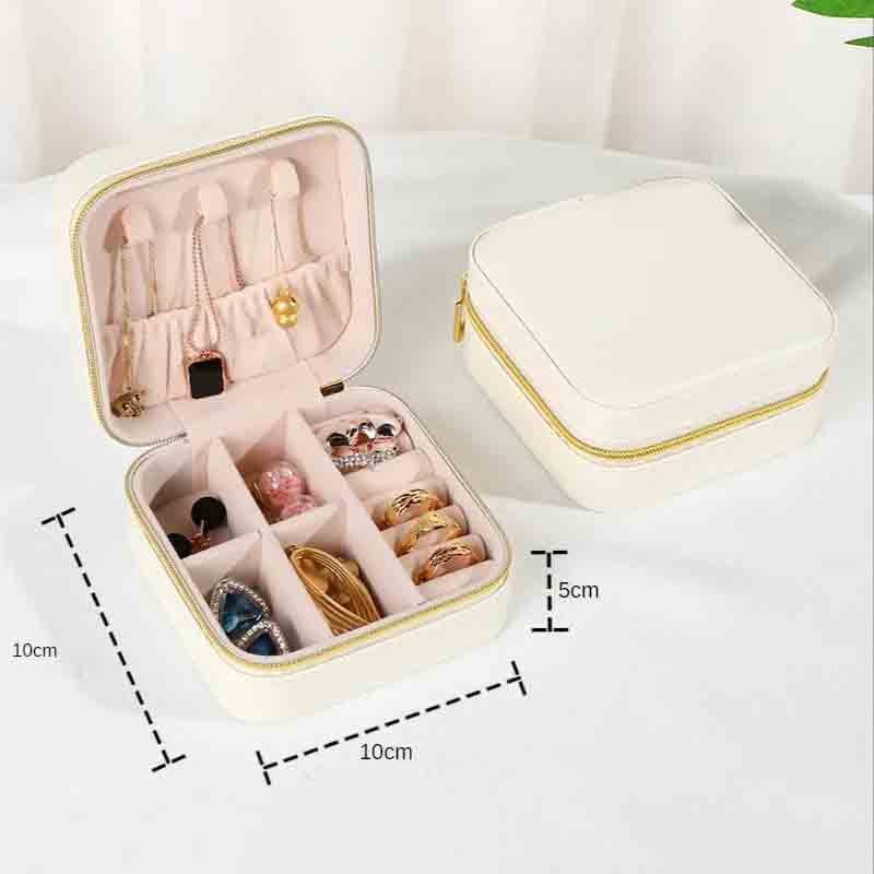 An open white square jewelry box with gold zipper and accents, filled with various necklaces, earrings, and rings, with a closed matching box in the background, showing dimensions of 10cm x 10cm x 5cm.