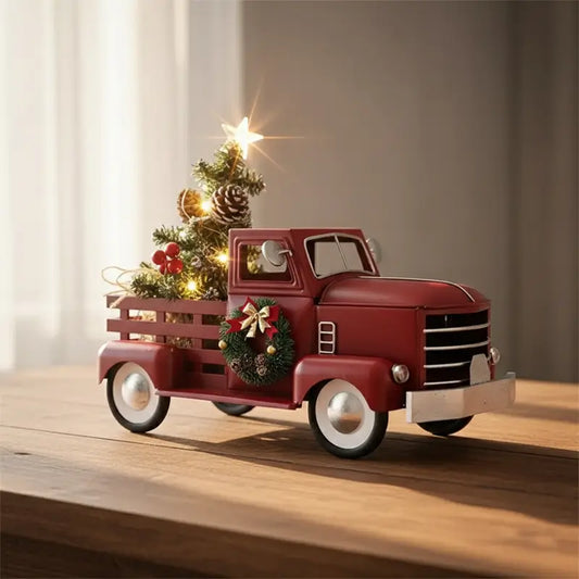 A miniature red truck carrying a Christmas tree, adorned with lights and a wreath.