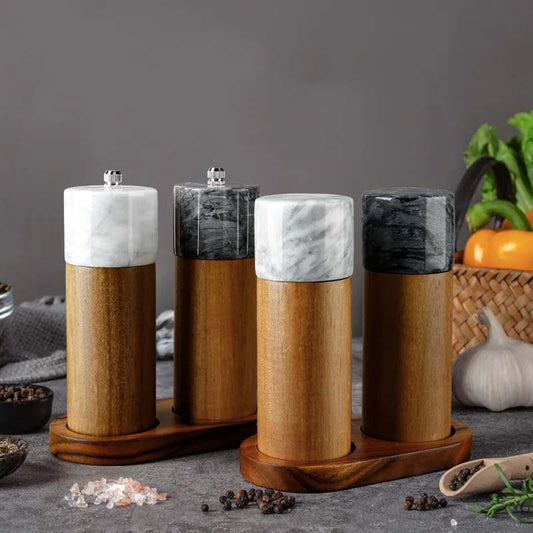 Four spice grinders with wooden bases and marble tops.