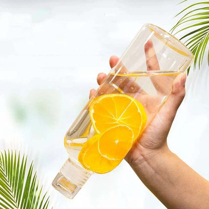 A hand holding a glass bottle with orange slices in water.
