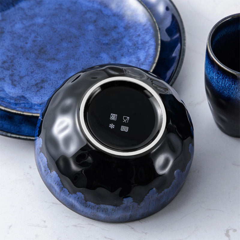 The bottom of a black and blue bowl, with microwave, dishwasher, and freezer safe icons visible.