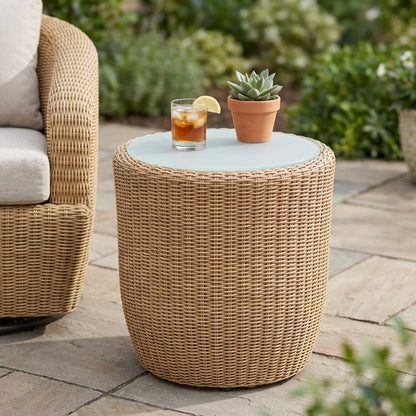 Round table top with a glass of iced amber tea with a lemon wedge and a small succulent in a terracotta pot, with part of a honey-tan rattan chair cropped at top left