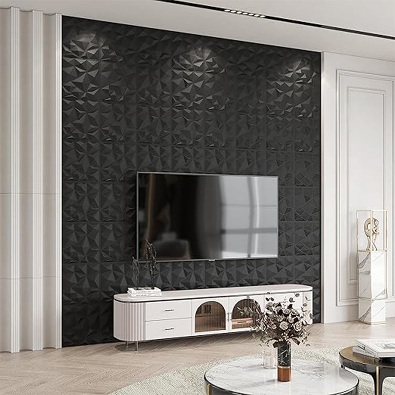 A modern living room with a black geometric textured accent wall, a mounted TV, a white media console, and a round coffee table with flowers.