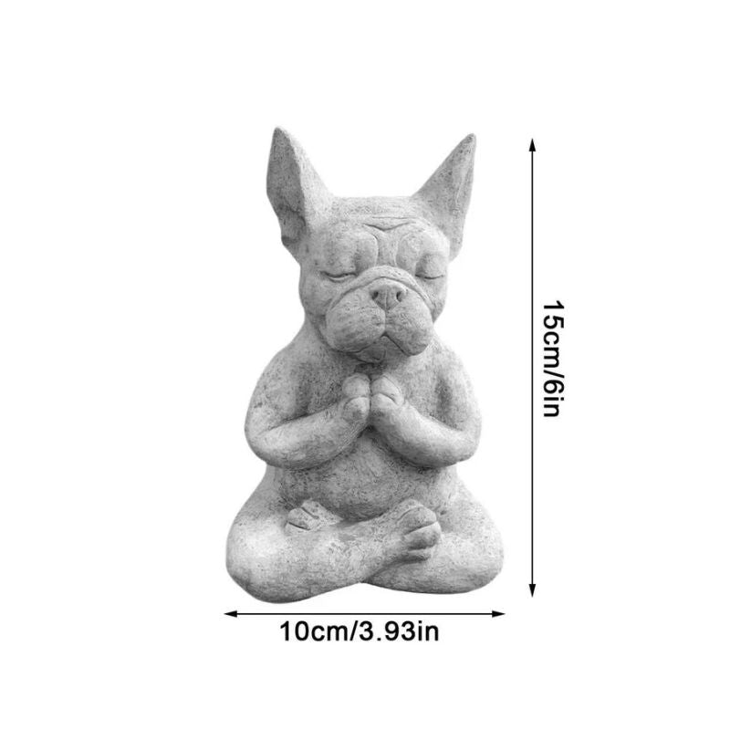 A grayscale image shows a stone-like figurine of a French Bulldog sitting in a meditative yoga pose with its eyes closed and paws pressed together. Arrows with labels indicate the figurine's dimensions: a vertical arrow labeled "15cm/6in" for height and a horizontal arrow labeled "10cm/3.93in" for width. The background is plain white.