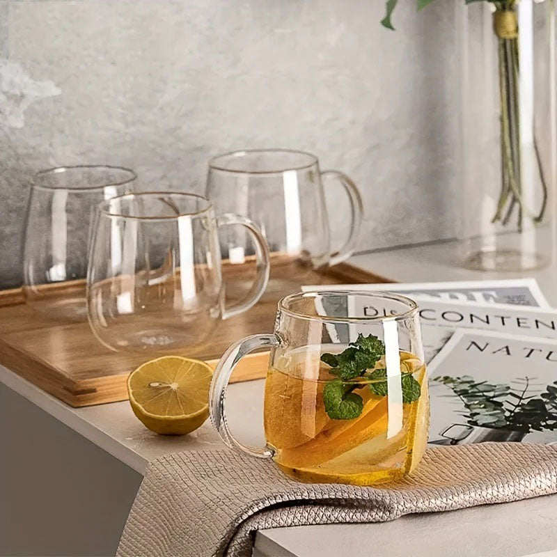A glass mug filled with a lemon and mint drink, with three empty glass mugs on a wooden tray behind it.