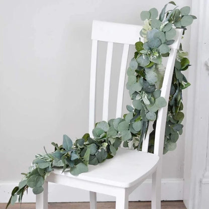 Artificial eucalyptus garland draped over a chair, adding a touch of natural beauty and sophistication to home decor with its lifelike leaves.