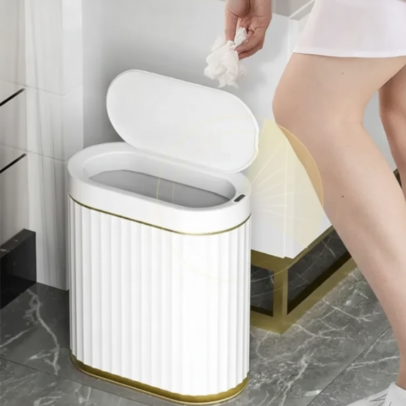 Tall, white, oval smart trash can with gold accents and vertical fluting.