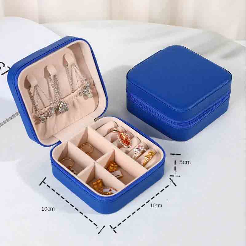 An open royal blue square jewelry box filled with various necklaces, earrings, and rings, with a closed matching box in the background, showing dimensions of 10cm x 10cm x 5cm.