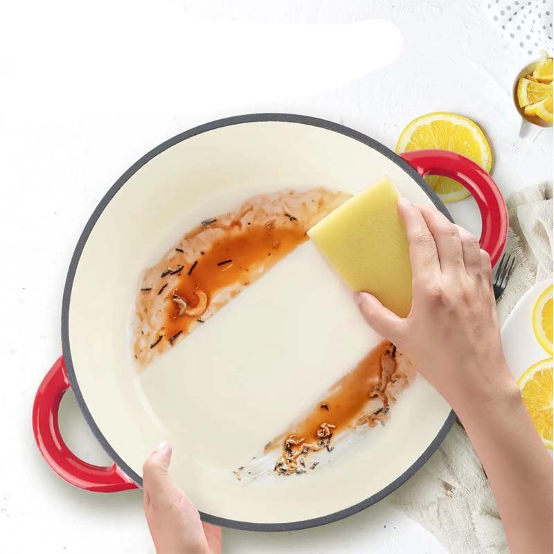 A person cleaning a dirty pan with a sponge.