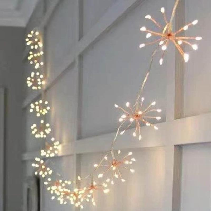 Decorative string lights shaped like fireworks on a white wall.