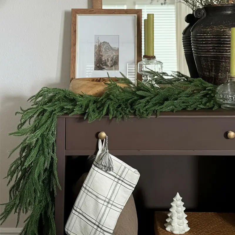A green garland draped over a dark console table.