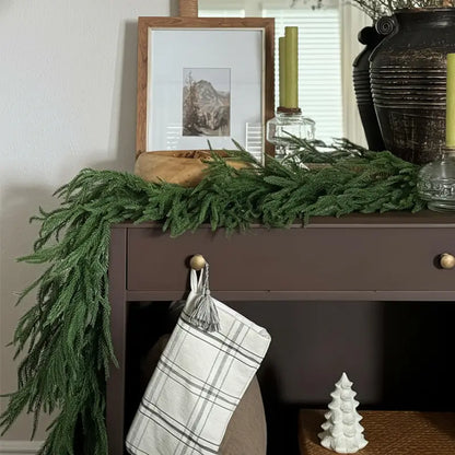 A green garland draped over a dark console table.