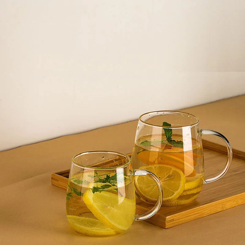 Two clear glass mugs of lemon and mint water on a bamboo tray.