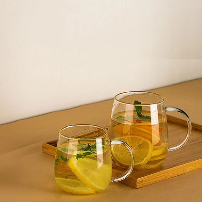 Two clear glass mugs of lemon and mint water on a bamboo tray.