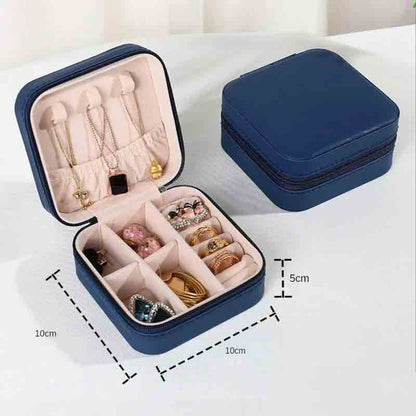 An open navy blue square jewelry box filled with various necklaces, earrings, and rings, with a closed matching box in the background, showing dimensions of 10cm x 10cm x 5cm.