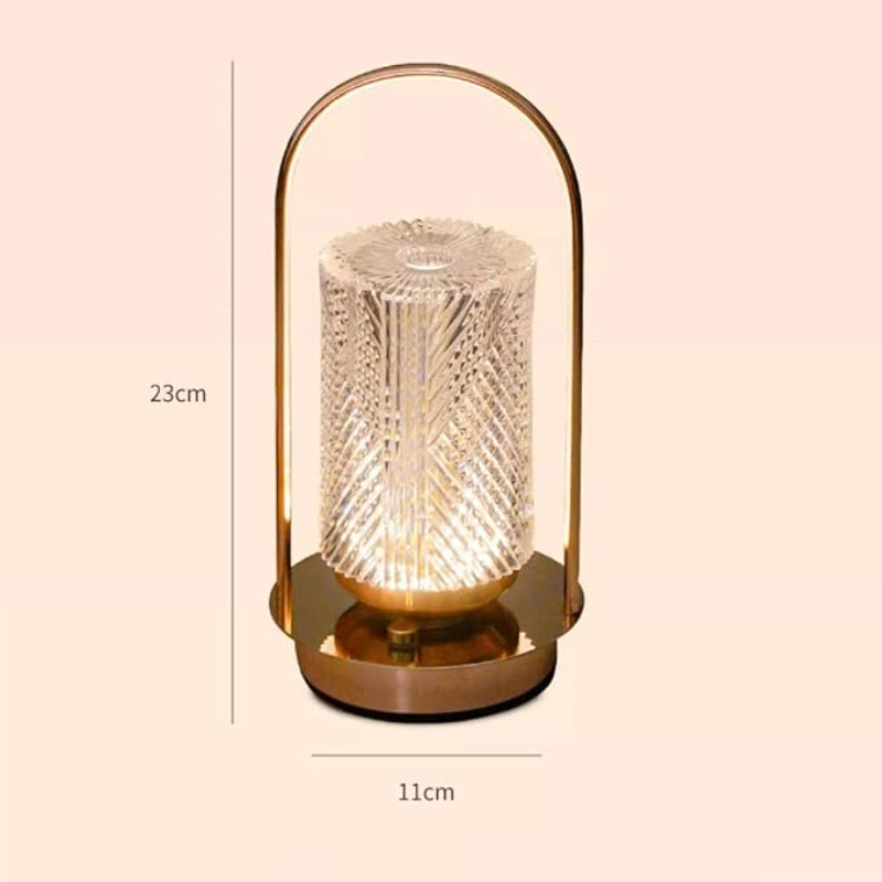 A glowing, portable, lantern-style lamp with a textured cylindrical glass shade and a gold-toned base and handle, with its dimensions of 23 cm tall and 11 cm wide noted beside it.