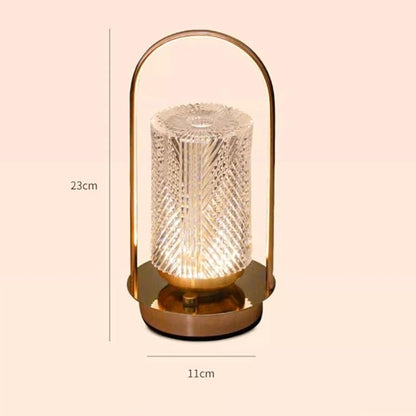 A glowing, portable, lantern-style lamp with a textured cylindrical glass shade and a gold-toned base and handle, with its dimensions of 23 cm tall and 11 cm wide noted beside it.