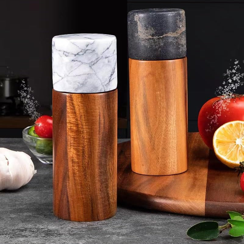 Two wooden salt and pepper shakers on a kitchen counter with ingredients in the background.