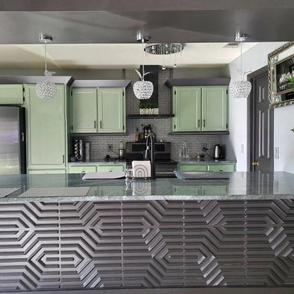 A modern kitchen with green cabinets, a grey patterned backsplash, and a breakfast bar with geometric textured panels.