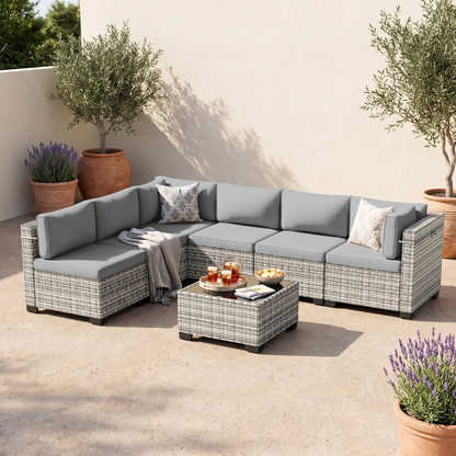 Gray-cushion 7-piece wicker outdoor sectional on a patio with olive trees