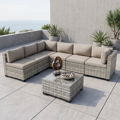 Gray-cushion 7-piece wicker outdoor sectional on a stone patio surrounded by greenery